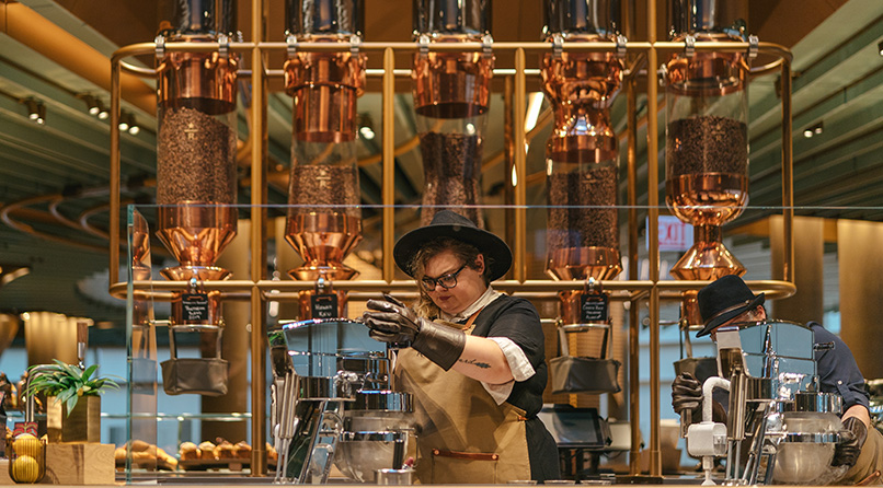 A person stands in front of a copper coffee bean display, skillfully crafting a small batch of nitrogen-infused gelato.