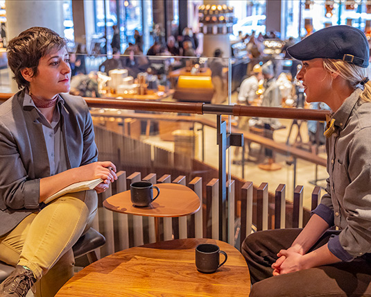 Two people sit at a table, engaged in conversation. 