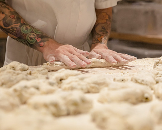 A close-up of hands rolling dough in a kitchen environment.