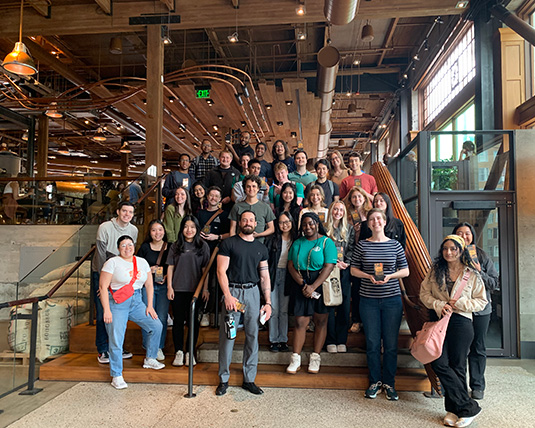 A large group of people stands at a Roastery Reserve store, posing in front of the camera.