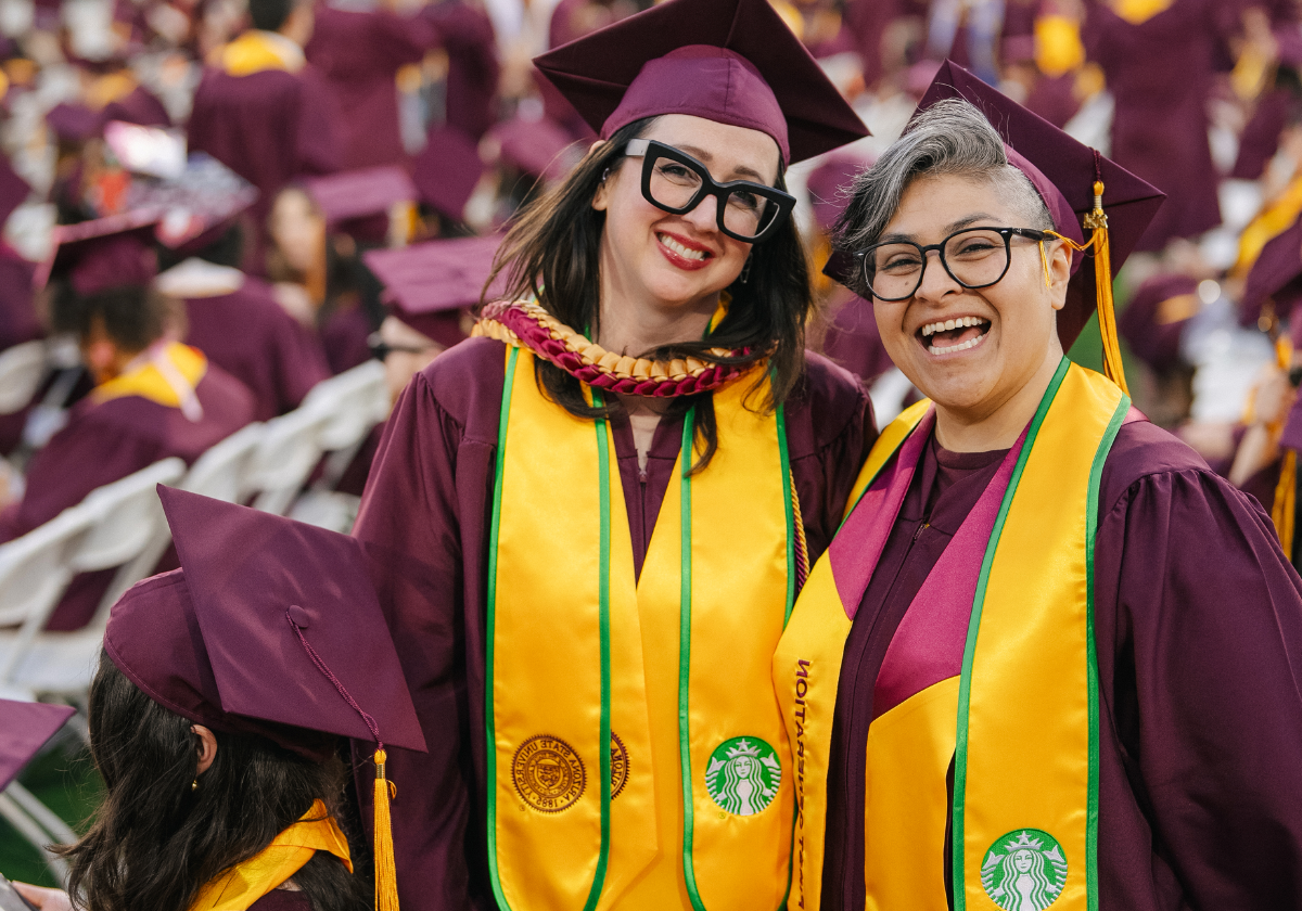 Two Starbucks employees stand at Arizona State University's graduation after receiving their bachelor degrees.