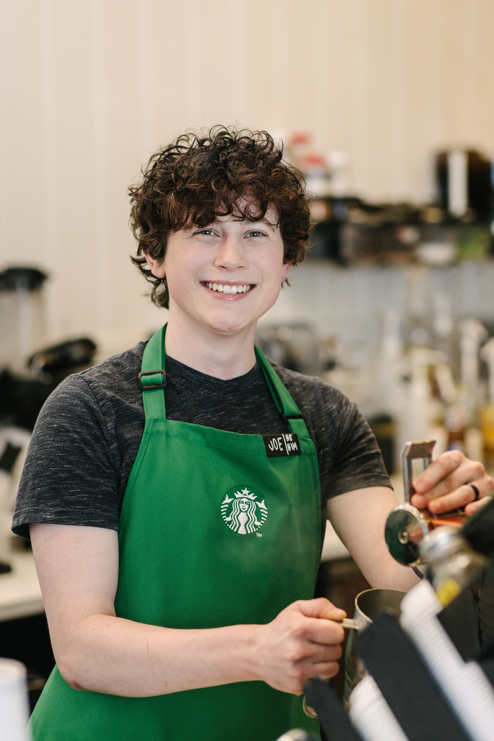 Une personne portant un tablier vert Starbucks se tient derrière le comptoir dans un magasin Starbucks.