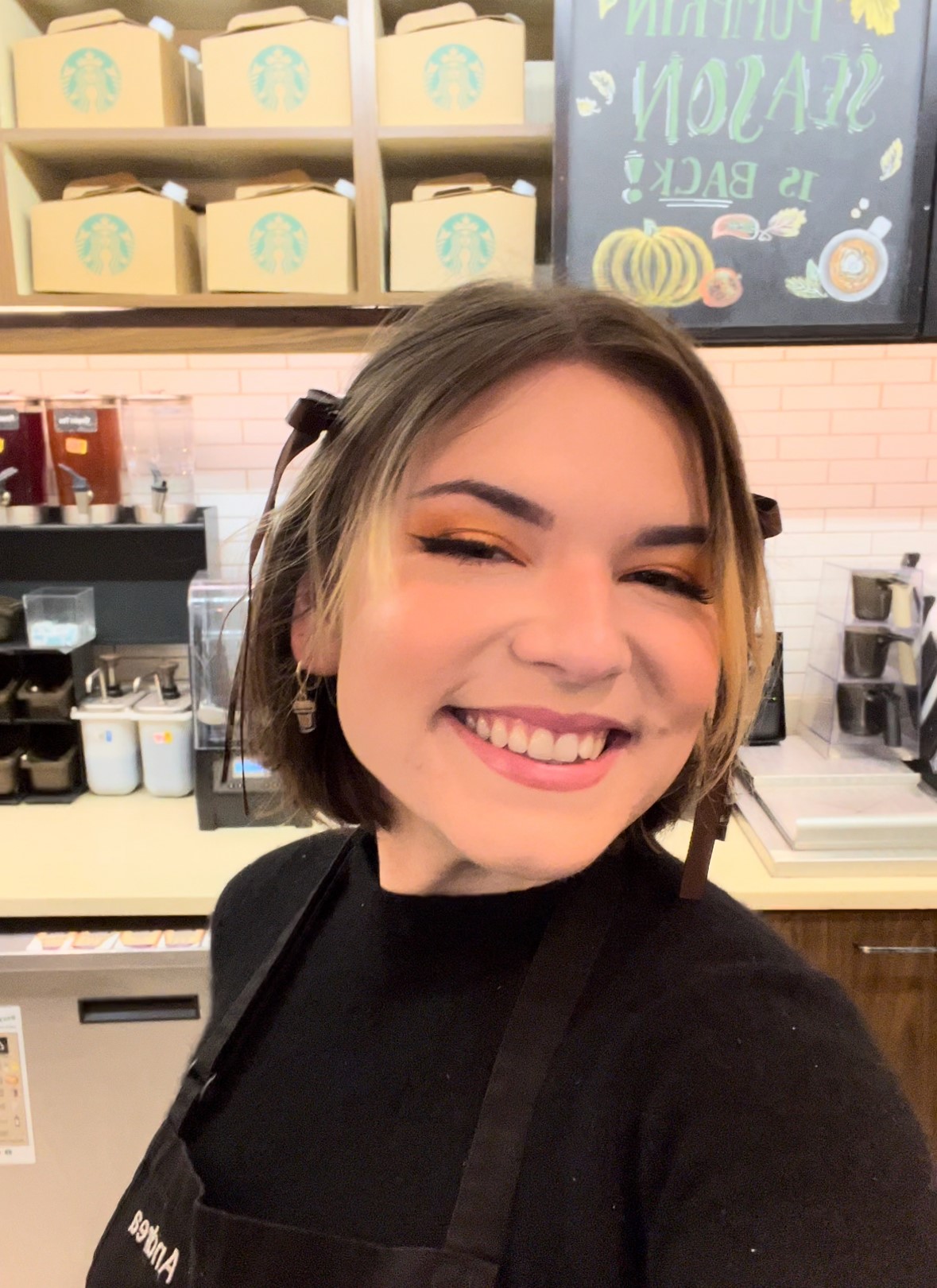 Une personne portant un casque d’écoute dans un magasin Starbucks prend la pose en souriant.