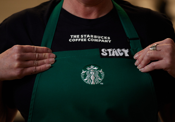 Un gros plan montre une barista Starbucks en train d’enfiler son tablier vert.